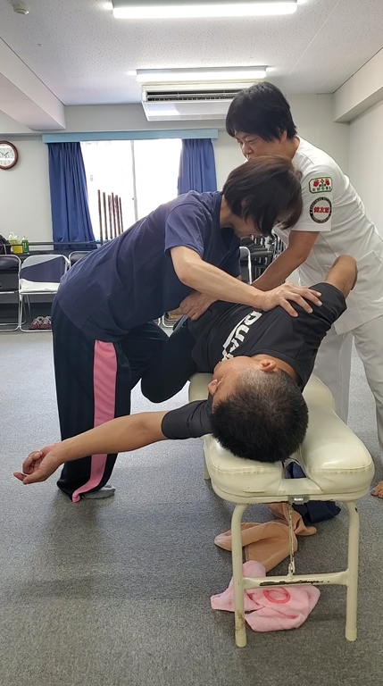 健友館整体師養成所の大阪市での出張実技講習会で講師からマンツーマン指導を受ける様子