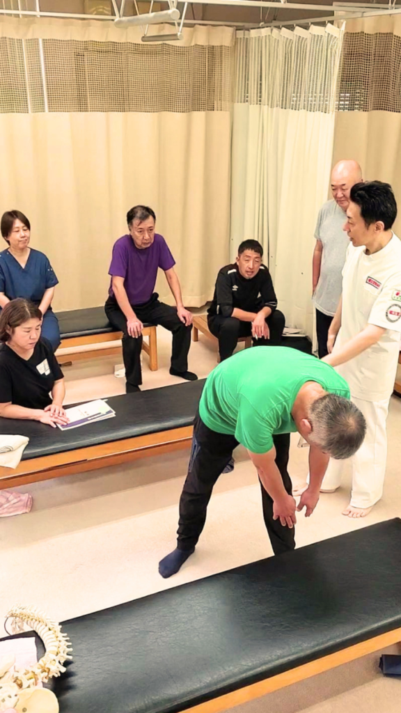 健友館整体師養成所で講師から整体技術の実技指導を受ける受講生