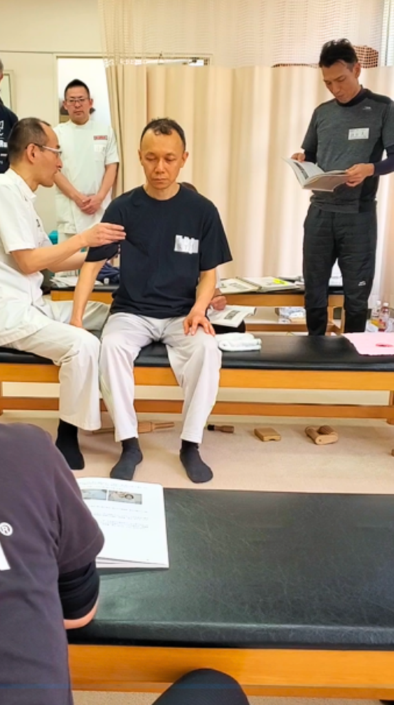 健友館整体師養成所で講師から整体技術の実技指導を受ける受講生