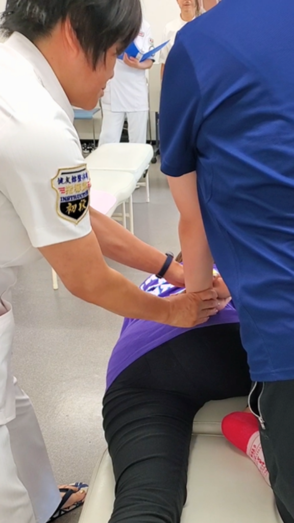 健友館整体師養成所で講師が受講生の手の位置を確認しながら整体技術を指導する様子