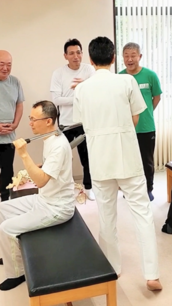 健友館整体師養成所で講師の指導を受けながら整体の基本技術を学ぶ受講生